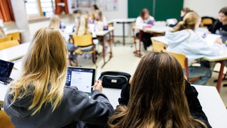 Schülerinnen einer sechsten Klasse arbeiten in einem Klassenraum während einer Unterrichtsstunde an ihren Tablets. 