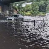 Ein Auto fährt durch eine überschwemmte Unterführung