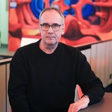 Ein Mann mit Brille in schwarzem Pullover, der Schriftsteller Volker Kutscher, sitzt an einem Tisch.