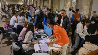 Eine große Halle zeigt Menschen bei der Stimmzettelauszählung der Präsidentschaftswahl in der Türkei am 15.05.2023