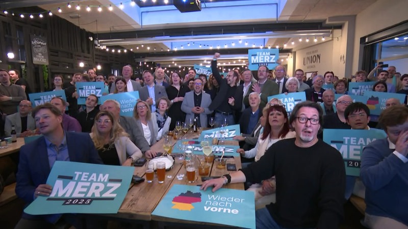 Die CDU in Bremen feiert die Wahlergebnisse mit Schildern und Merz-Plakaten.