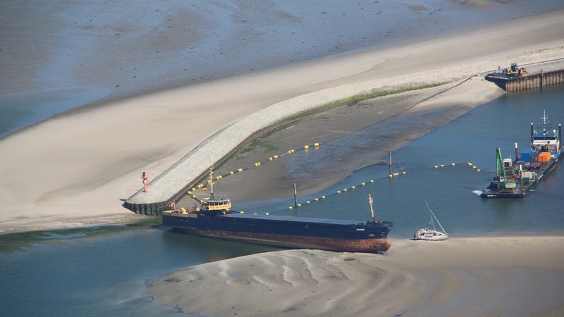 Ein Küstenmotorschiff liegt auf einer Sandbank