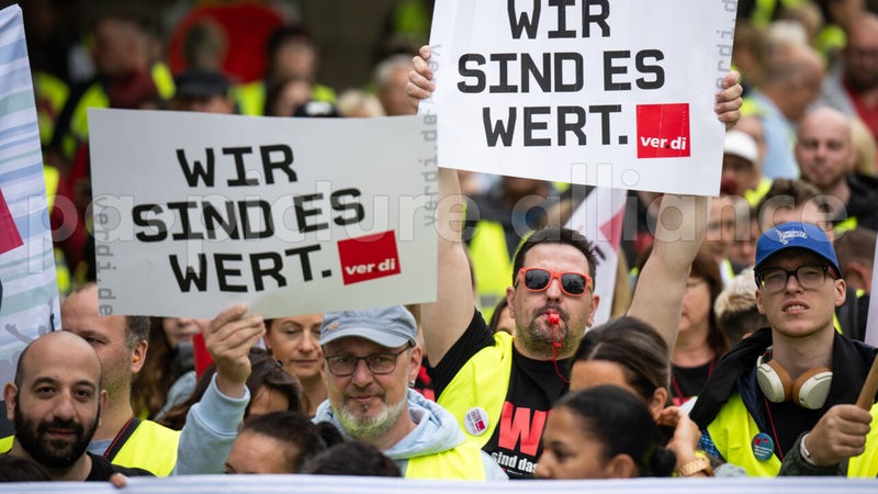 Streik-Teilnehmer halten Schilder hoch mit der Aufschrift "Wir sind es wert".