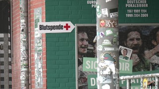 An einer Wand im Weserstadion ist ein Schild mit der Aufschrift "Blutspende" befestigt.