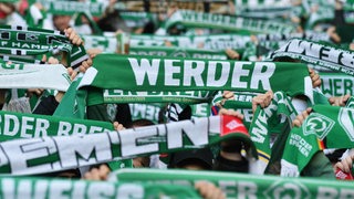 Werderfans halten ihre Schals in die Höhe.