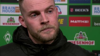 Werder-Stürmer Marvin Ducksch steht vor einer Werbewand nach dem Spiel beim Interview.