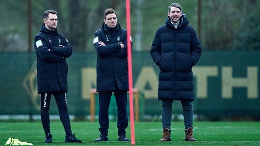 Physiotherapeut Claas Bente, Clemens Fritz und Peter Niemeyer stehen beim Training am Spielfeldrand.