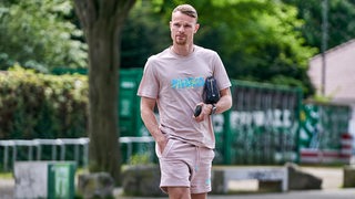 Christian Groß läuft in Freizeitkleidung am Weser-Stadion entlang.