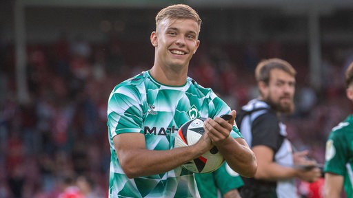 Keke Top grinst nach dem Spiel gegen Cottbus und hält den Spielball in der Hand.