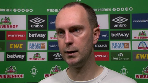 Werder-Trainer Ole Werner vor einer Werbewand beim Interview nach dem Spiel gegen Schalke.