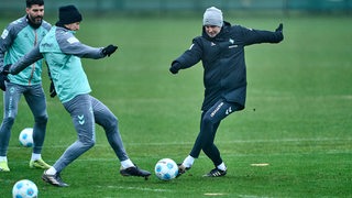 Ole Werner geht im Training mit dem Ball am Fuß in den Zweikampf mit Niklas Stark. Anthony Jung schaut dabei zu. 