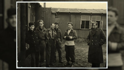 Historisches Foto mehrerer kriegsgefangener Seeleute vor einer Baracke