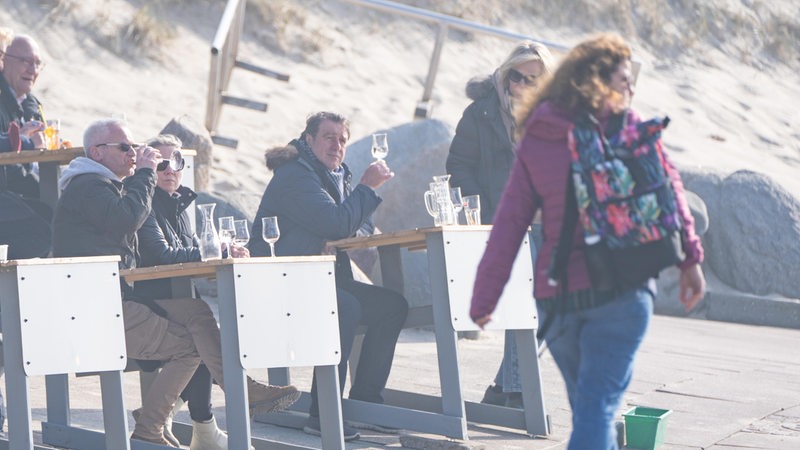 Menschen sitzen in dicken Jacken in einer Strandbar an der Nordsee.