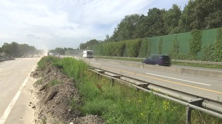 Autos fahren auf der Autobahn an einer Baustelle vorbei.