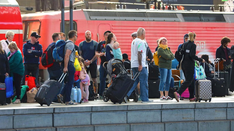 Fahrgäste stehen wartend auf einem Bahngleis